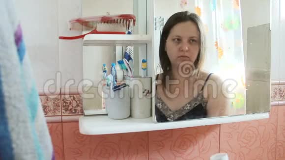 超重长发女人在浴室刷牙穿着蓝色睡衣的女孩倒映在镜子里视频的预览图