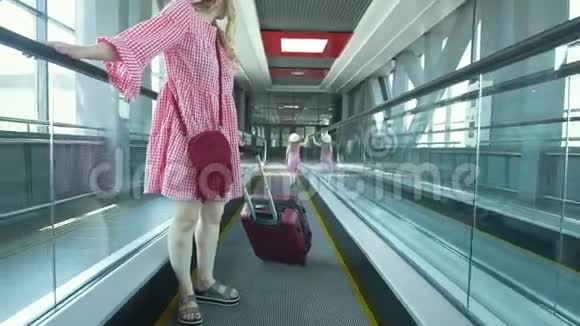 年轻漂亮的女人带着手提箱从扶梯上下来她漂亮的女儿在门口追赶她的母亲视频的预览图