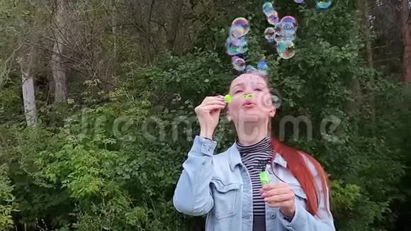 一个夏天的晚上年轻的女人在公园里吹泡泡视频的预览图