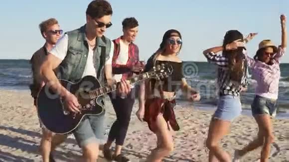 一群年轻的嬉皮士朋友一起在沙滩上玩吉他和唱歌跳舞视频的预览图
