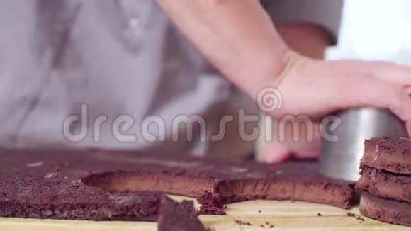 糕点师的手从巧克力面团中切出圆形蛋糕视频的预览图