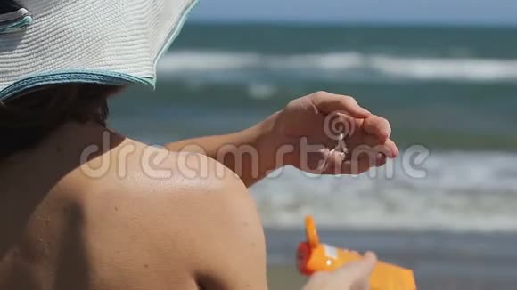 在阳光充足的沙滩上进行日光浴使用防晒化妆品的女性视频的预览图
