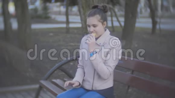 在户外吃热狗的少女在公园里吃热狗的漂亮少女视频的预览图