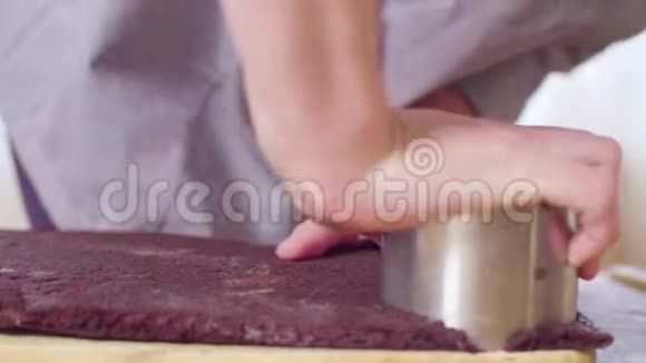 糕点师的手从巧克力面团中切出圆形蛋糕视频的预览图