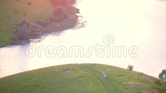 从山上俯瞰空中景色在夏日日落时母亲和小女儿在草地上玩得很开心视频的预览图