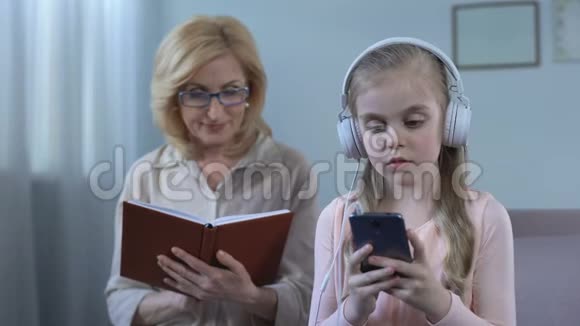 女孩戴着耳机听音乐和奶奶看书代沟视频的预览图