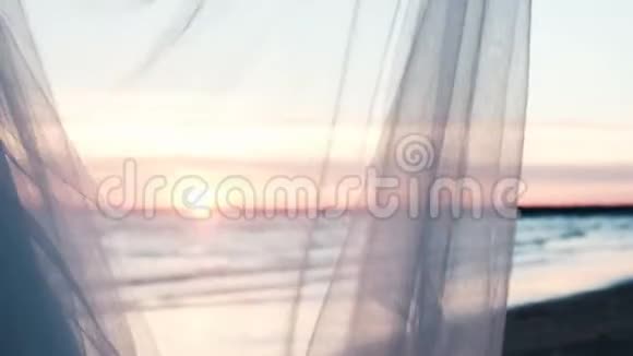 女人的手握着透明的布料裙子在夕阳的映衬下随风飘扬视频的预览图
