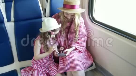 年轻的白种人妈妈和女儿抱着火车用手机视频的预览图