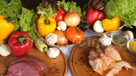 在生菜叶香料咖喱辣椒等蔬菜的背景下木板上摆放着不同种类的肉视频的预览图