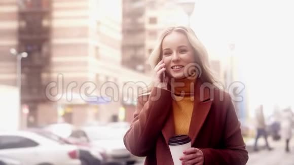 时髦的女人走在街上会说话的智能手机视频的预览图