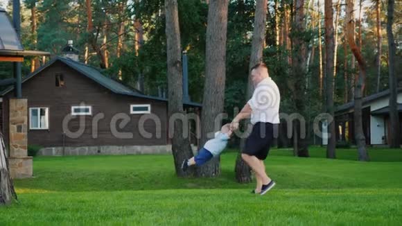一位健康的父亲在他家的院子里和他的小儿子玩耍视频的预览图