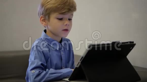 穿蓝色衬衫的男孩在平板电脑上工作视频的预览图