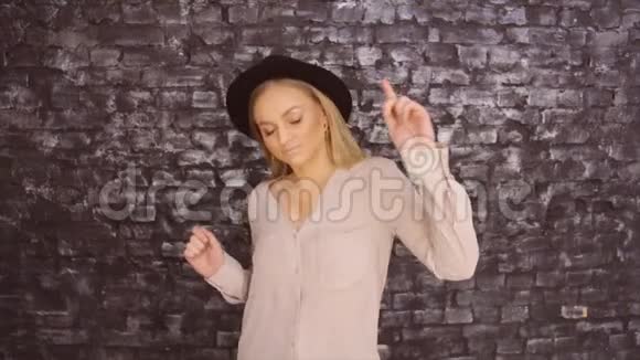 一个戴着黑帽子的女孩正在一面有质感的墙上跳舞视频的预览图
