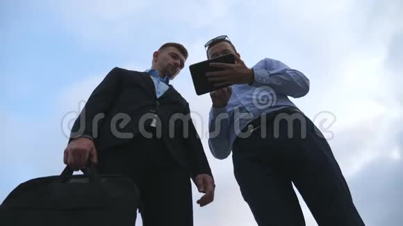 两位年轻商人在户外聊天和使用平板电脑商人们在外面的天空中工作视频的预览图