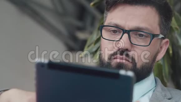 戴眼镜和胡子的商人在大厅里用平板电脑工作视频的预览图