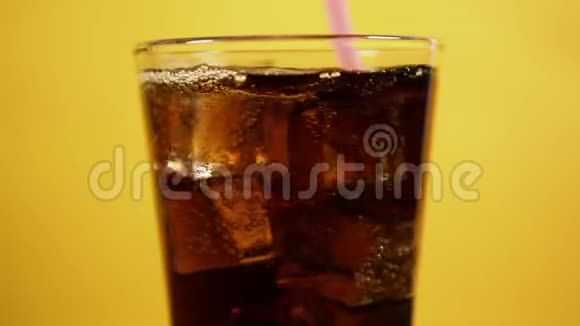 把可乐和粉红色的吸管混合在一起盛满可乐汽水冰块的玻璃杯视频的预览图