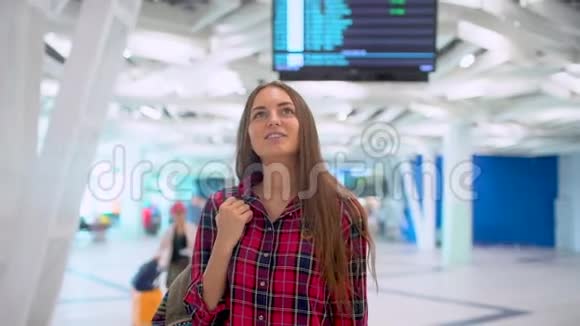 年轻的旅行女性穿着休闲衬衫带着行李在现代机场航站楼里行走城市机场旅游视频的预览图