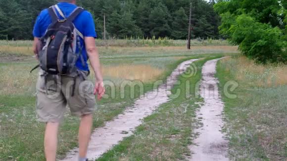 夏天徒步旅行者背着背包在乌克兰的沙地乡村公路上行走视频的预览图