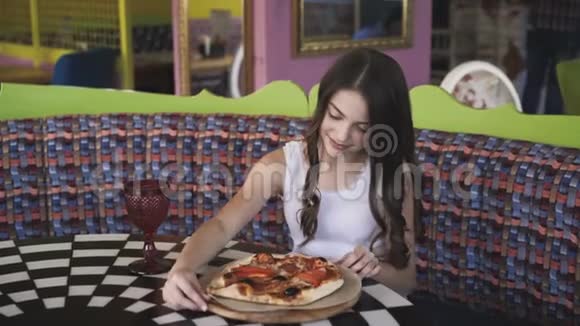 微笑的女孩在咖啡馆里旋转着欣赏着披萨的展示4K视频的预览图