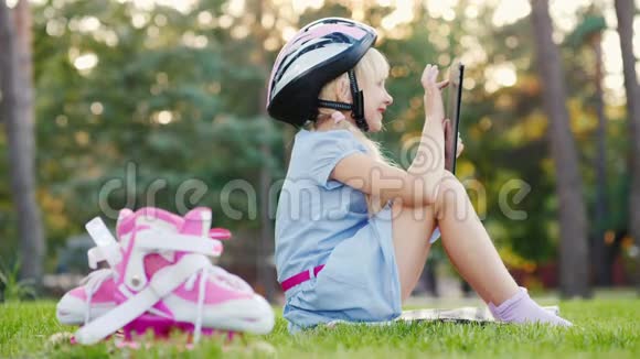 一个戴着防护头盔的女孩正在平板电脑上玩耍旁边是溜冰鞋视频的预览图