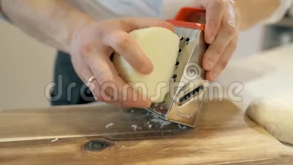 厨师磨碎磨碎的奶酪把奶酪煮在烤架上用手揉搓视频的预览图