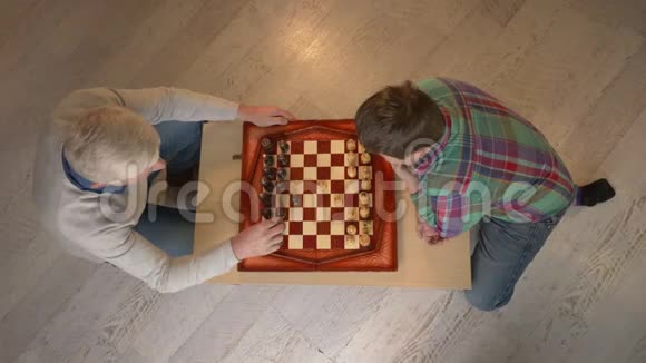祖父和孙子下棋老人教棋玩小胖孩家庭舒适家庭懒散视频的预览图