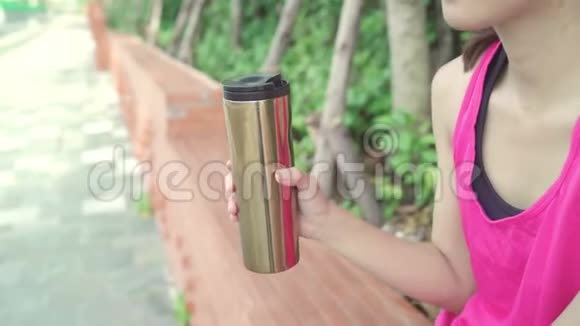 健康美丽的年轻亚洲跑步女子饮水因为在城市公园街头跑步后感到疲倦视频的预览图