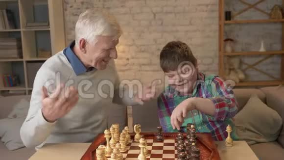祖父和孙子下棋老人教棋玩小胖孩家庭舒适家庭懒散视频的预览图