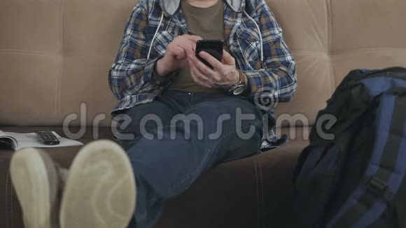 一个坐在沙发上的人在智能手机上使用互联网旁边是一个大型旅游背包视频的预览图