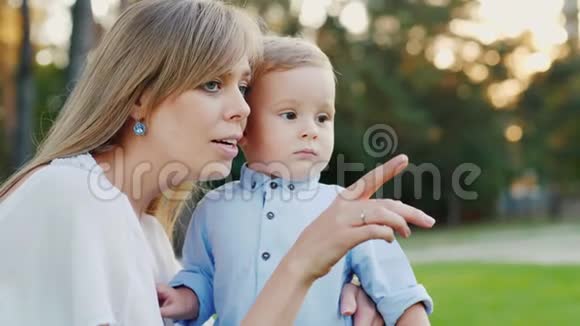 一位年轻的母亲和她的小儿子在公园里散步妈妈给孩子看了一些有趣的东西视频的预览图