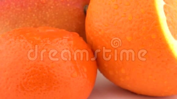 芒果橙果和柑果的宏观皮肤上有水滴在白色背景上旋转孤立无援视频的预览图