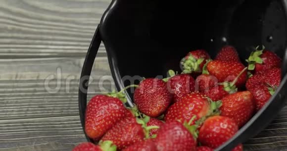 木桌上一个黑色小桶里的草莓合上视频的预览图