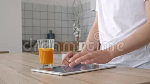 科技家庭饮料和生活方式的概念用平板电脑和一杯橙汁在家中接近男人视频的预览图