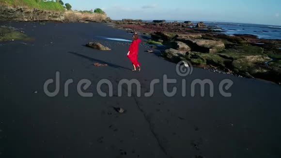 在黑色波光粼粼的沙滩上观看美丽性感的比基尼女郎和红色的整体造型视频的预览图