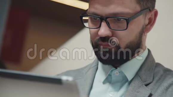 一个留着胡子戴着眼镜的人穿着商务套装使用一个小玩意视频的预览图