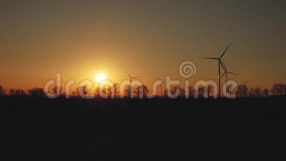 日落时树木背景上的风力发电机风力发电厂视频的预览图