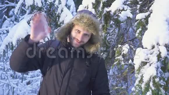 冬季森林旅行者带背包向相机挥手冬天森林里阳光明媚的早晨视频的预览图