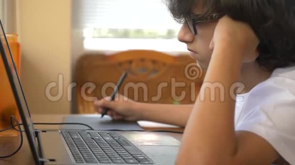 英俊的现代男孩在制作一个图形平板电脑他看着笔记本电脑的屏幕4k慢动作视频的预览图
