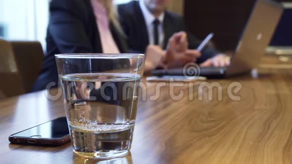 特写一杯水和一个躺在桌子上的iPhone视频的预览图