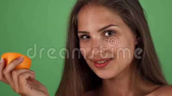 快乐的美丽的女人微笑着手里拿着一个橘子视频的预览图