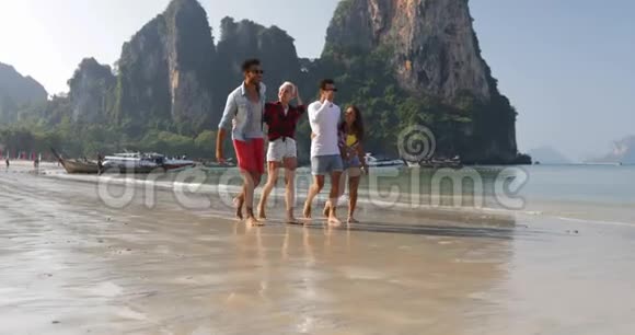 人们在沙滩上散步聊天两对情侣牵手快乐男女游客度假视频的预览图