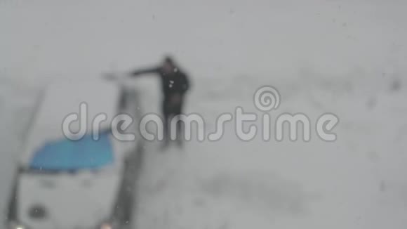 雪落在一个男人在停车场挖他的车的背景上视频的预览图