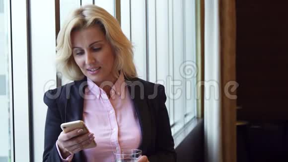 女商人喝水看手机里的照片视频的预览图
