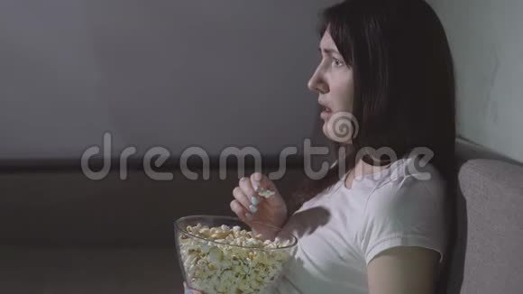 美丽的年轻女子独自在看恐怖电影视频的预览图