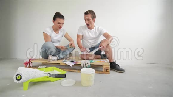 幸福的年轻夫妇规划设计项目为他们的公寓坐在地板上白色墙壁上的彩色调色板视频的预览图