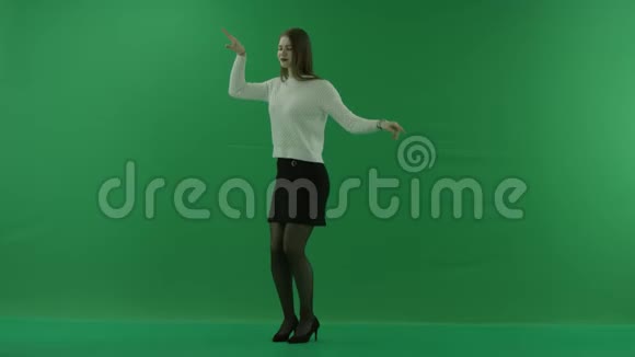 女孩正站在半个转弯处看着左边在绿色的屏幕上跳舞视频的预览图