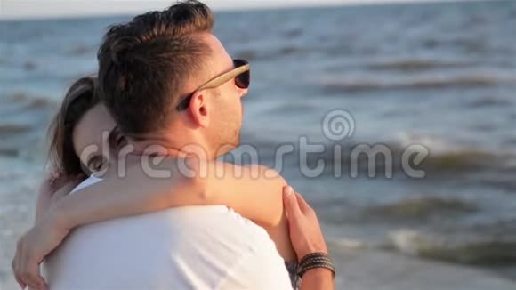 恋爱中的年轻夫妇在波浪背景下拥抱大海的背景视频的预览图