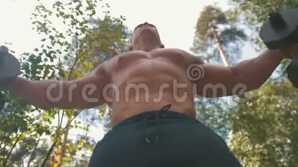 肌肉健美运动员举起一个沉重的铁哑铃在森林中锻炼视频的预览图