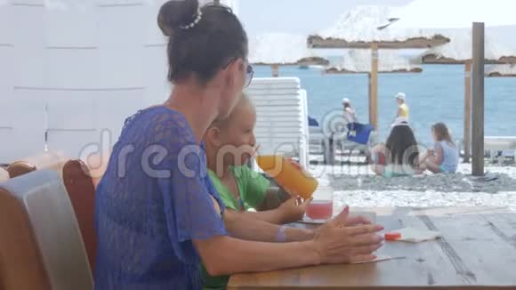 年轻的母亲和小可爱的女儿坐在海景咖啡馆视频的预览图