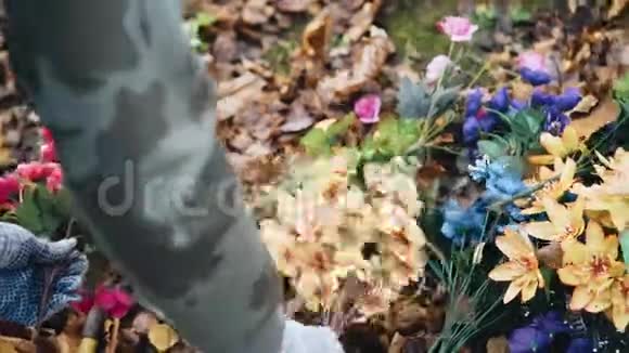 戴手套的女孩从地上收集人造花双手合拢秋天视频的预览图